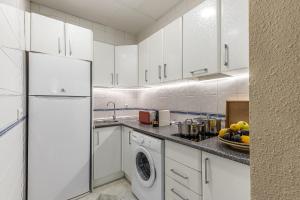 una cucina con mobili bianchi e un frigorifero bianco di Waou Sevilla Centro II a Siviglia