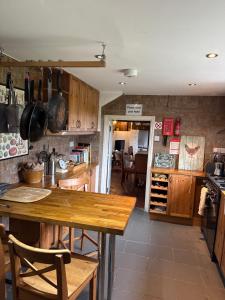 a kitchen with wooden cabinets and a wooden table at Cricketers cottage in Tirley