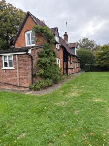 a brick house with a green lawn in front of it at Cricketers cottage in Tirley +3 photos
