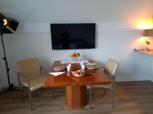 a dining room table with chairs and a television at Room by the sea in Zoutelande