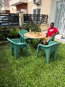 a woman sitting at a table and chairs in the grass at EMY guest HOUSE in Kofa