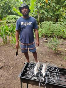 a man standing next to a grill with two chickens at Loh jinawi Guest House Bunaken in Bunaken
