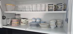 a shelf filled with cups and plates and bowls at Apartman BINGO Bugojno in Bugojno +8 photos