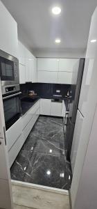 a kitchen with white cabinets and a black tile floor at Apartman BINGO Bugojno in Bugojno