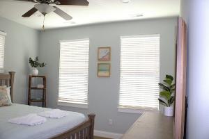 a bedroom with three windows with white shutters at 410A The Jetty House in Virginia Beach
