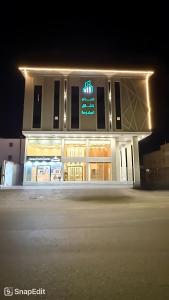 a building with a neon sign in front of it at Asdan Hotel in Al Ahsa