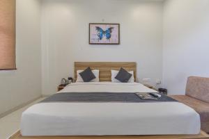 a bedroom with a large white bed and a chair at HOTEL OXUS, Pratap Nagar in Jaipur
