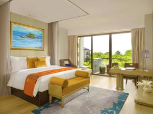 una camera con un grande letto e una scrivania e un computer di Mövenpick Resort & Spa Jimbaran Bali a Jimbaran