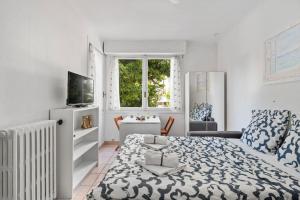 Una habitación blanca con una cama y un televisor. en LE GLORIA - Hyper Centre - Proche Mer - Wifi, en Menton