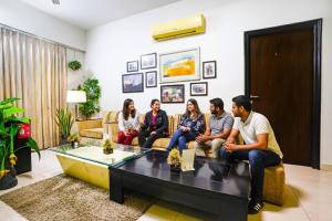 eine Gruppe von Menschen, die in einem Wohnzimmer auf einer Couch sitzen in der Unterkunft FabHotel Mumbai Corporate Apartments Bandra in Mumbai
