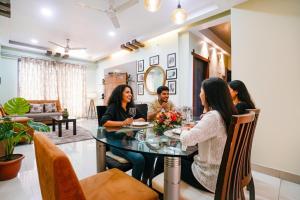 eine Gruppe von Personen, die in einem Wohnzimmer am Tisch sitzen in der Unterkunft FabHotel Mumbai Corporate Apartments Bandra in Mumbai
