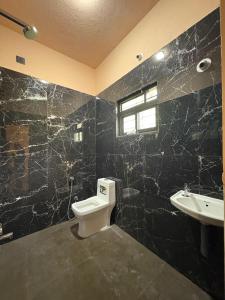 La salle de bains noire est pourvue de toilettes et d'un lavabo. dans l'établissement Village View Gokarna, à Gokarna