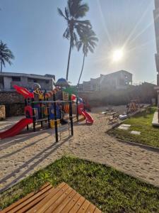 a playground on the beach with a palm tree in the background at Almasi Suites at Sandyshore Beach Resort in Kikambala