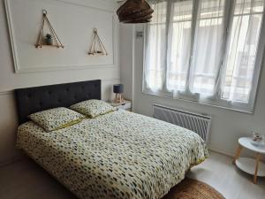 Un dormitorio con una cama con edredón y una ventana. en Studio cocooning proche plage & centre, en Trouville-sur-Mer