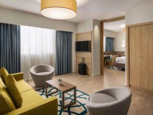 ジッダにあるAdagio Jeddah City Centerのソファ、椅子、ベッドが備わるホテルルームです。