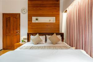 a bedroom with a white bed and a clock on the wall at HSR Penthouse Spacious 4-BHK Apartment with Living, Lounge Area, Study Room, Terrace & Balconies in Bengaluru