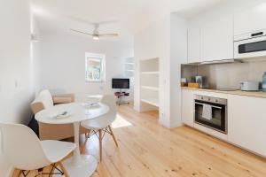 a white kitchen with a white table and chairs at Alfama Fado Apartments in Bicas