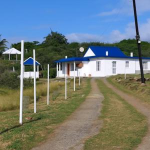a road leading to a white building with a blue roof at Palawan Holiday Lodge in Port Mathurin