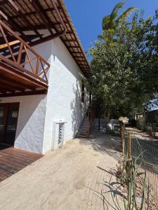 un bâtiment blanc avec un escalier et un arbre dans l'établissement Suítes BG - Rua principal de Barra Grande, à Barra Grande