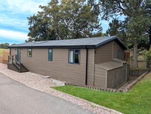 a small brown building with a staircase in a yard at Hot Tub, Lake View, Peaceful Woodland Retreat in Eaton