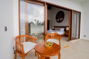 ウブドにあるThe Surana Villas Ubud with Rice Field Viewのテーブル、椅子2脚、ベッド1台が備わる客室です。