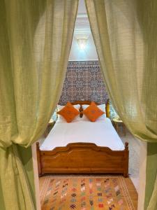 a bed with orange pillows in a room with curtains at Riad Dahab in Marrakech