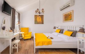 1 dormitorio con cama, escritorio y sillas amarillas en Villa Mia, en Sveti Ivan Dobrinjski