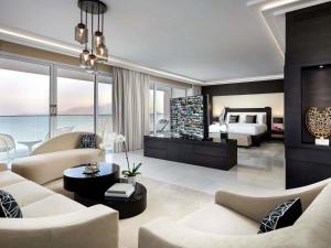 ein Wohnzimmer mit einem Bett und ein Zimmer mit einem Sofa in der Unterkunft Fairmont Fujairah Beach Resort in Al Aqah