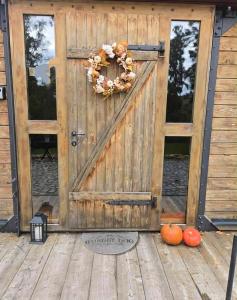 a wooden door with a wreath and pumpkins on a porch at Obytný vagón in Kamberk