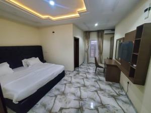 a hotel room with a bed and a desk and a television at Prym Hotel in Owerri