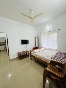 une chambre avec un lit et une télévision à écran plat dans l'établissement Manikya Homestay, à Malpe
