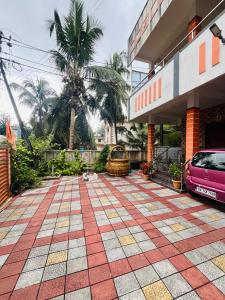 une voiture rose garée devant un bâtiment dans l'établissement Manikya Homestay, à Malpe