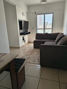 Una sala de estar con un sofá y un televisor. en apartamento próx shopping, en Taubaté