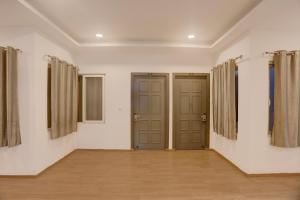 an empty room with two doors and curtains at Townhouse Mumfordganj in Prayāg
