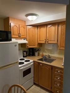 a kitchen with wooden cabinets and a white stove top oven at Midstream Manor Unit 1, Studio in St. John's
