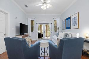a living room with blue chairs and a tv at Happy Days - Seagrove Highlands in Santa Rosa Beach