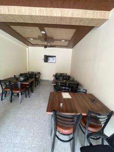 Un comedor con mesas y sillas de madera. en Hotel Midway Inn, en Jagatsukh 16 fotos más