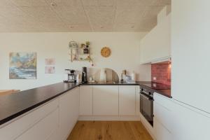 a kitchen with white cabinets and a black counter top at Unwind in Style - 2 BR - Hiking - Family in Tórshavn +15 photos