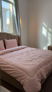 a bed with pink sheets in a bedroom with a window at Khalifa A Home Stay NR in Abu Dhabi