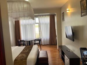a hotel room with a bed and a table and window at Majestic Nile Hotel Limited in Pakwach