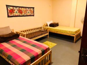 a room with two beds and a blanket on the wall at Hotel mango tree nearest Adam's peak in Adams Peak