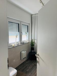 a bathroom with a toilet and two windows at FeWo S26 in Krumbach +14 photos
