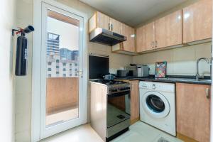 a kitchen with a washing machine and a washer at Royal Tulip Apartments in Sharjah