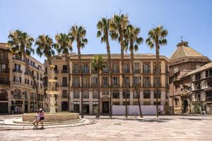 two people standing in front of a building with palm trees at NOMADIA en LARIOS STREET in Málaga
