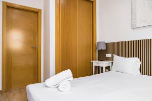 a bedroom with a bed with white sheets and a wooden door at NOMADIA en LARIOS STREET in Málaga