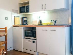 a kitchen with white cabinets and a microwave at Studio avec balcon, parking et Wi-Fi au cœur de Brides-les-Bains - FR-1-512-266 in Brides-les-Bains +9 photos
