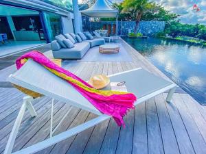 a white bench with a towel on it next to a pool at Very comfortable house fully equipped in Le Robert