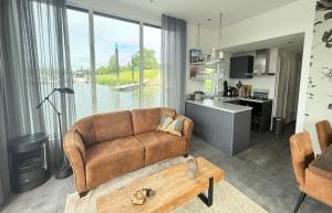 a living room with a brown couch and a kitchen at Woonboot 1 - Maasterp in Montfort