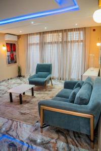 een woonkamer met een blauwe bank en twee stoelen bij Immeuble 30 Juin in Lubumbashi