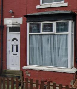 a red house with a white door and a window at 4BR - 8 Beds - Free Parking - Long stay Discounts in Killingbeck